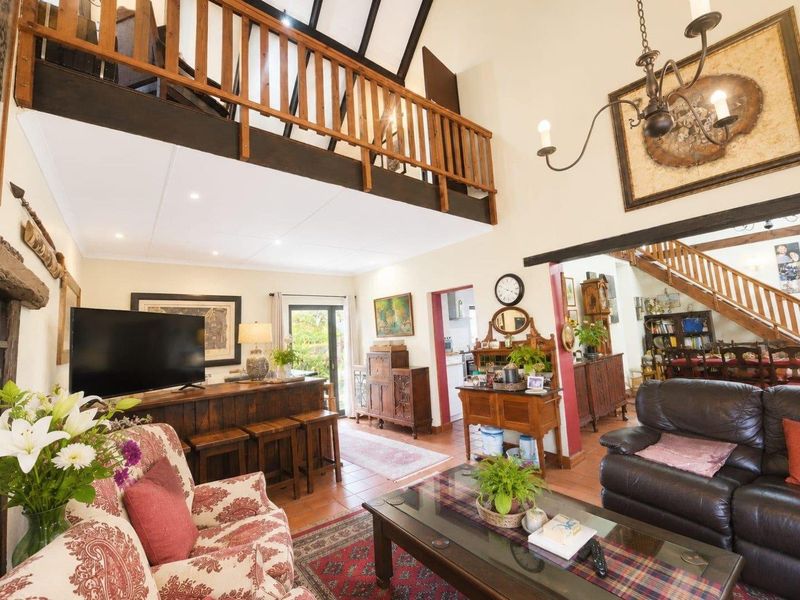 Spacious open-plan living area featuring a mezzanine level, exposed ceiling beams, terracotta flooring, and a built-in bar counter with direct access to the outdoors.