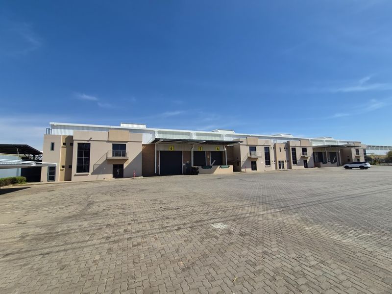 A large industrial warehouse facility featuring multiple loading docks, roller shutter doors, and a spacious paved yard area.