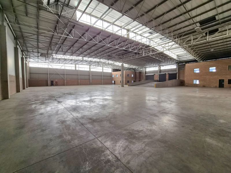 Spacious industrial warehouse featuring high ceilings with skylights, concrete flooring, and an internal loading ramp for efficient logistics and storage operations.