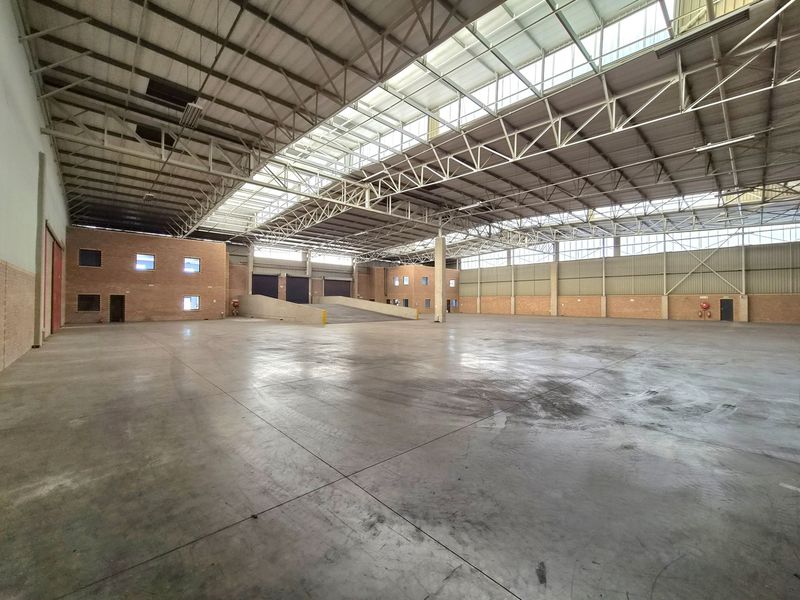 Spacious industrial warehouse featuring high ceilings with integrated skylights, concrete flooring, and a dedicated internal loading ramp for efficient logistics operations.