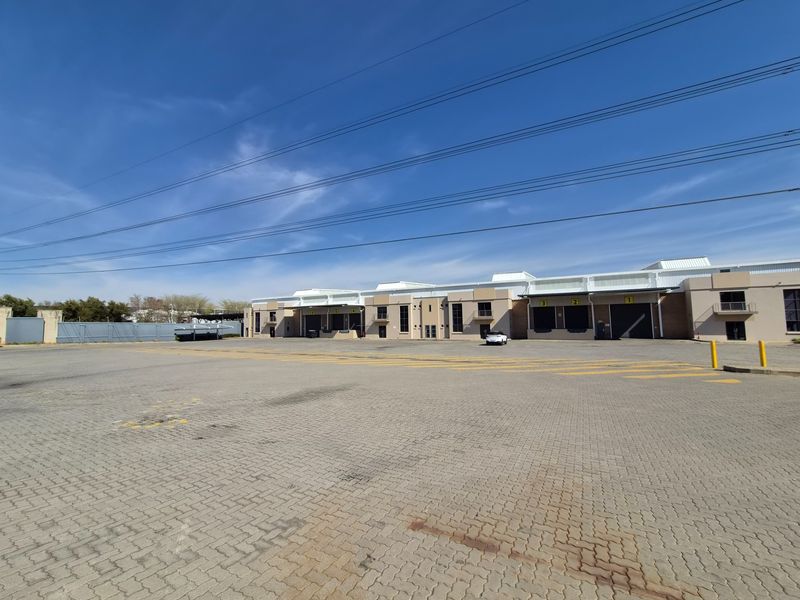 Wide-angle view of an industrial property featuring a large paved yard and multiple loading bays with roller shutter doors.