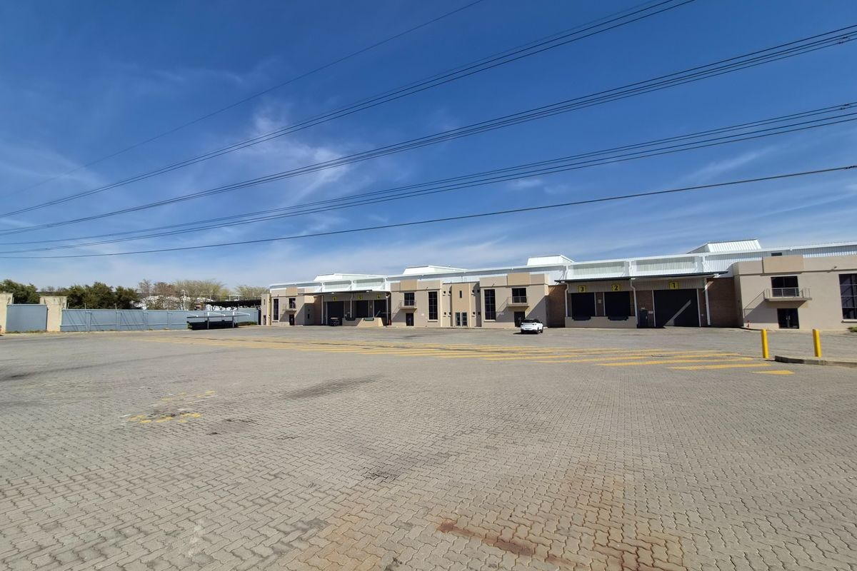 Wide-angle view of an industrial property featuring a large paved yard and multiple loading bays with roller shutter doors.