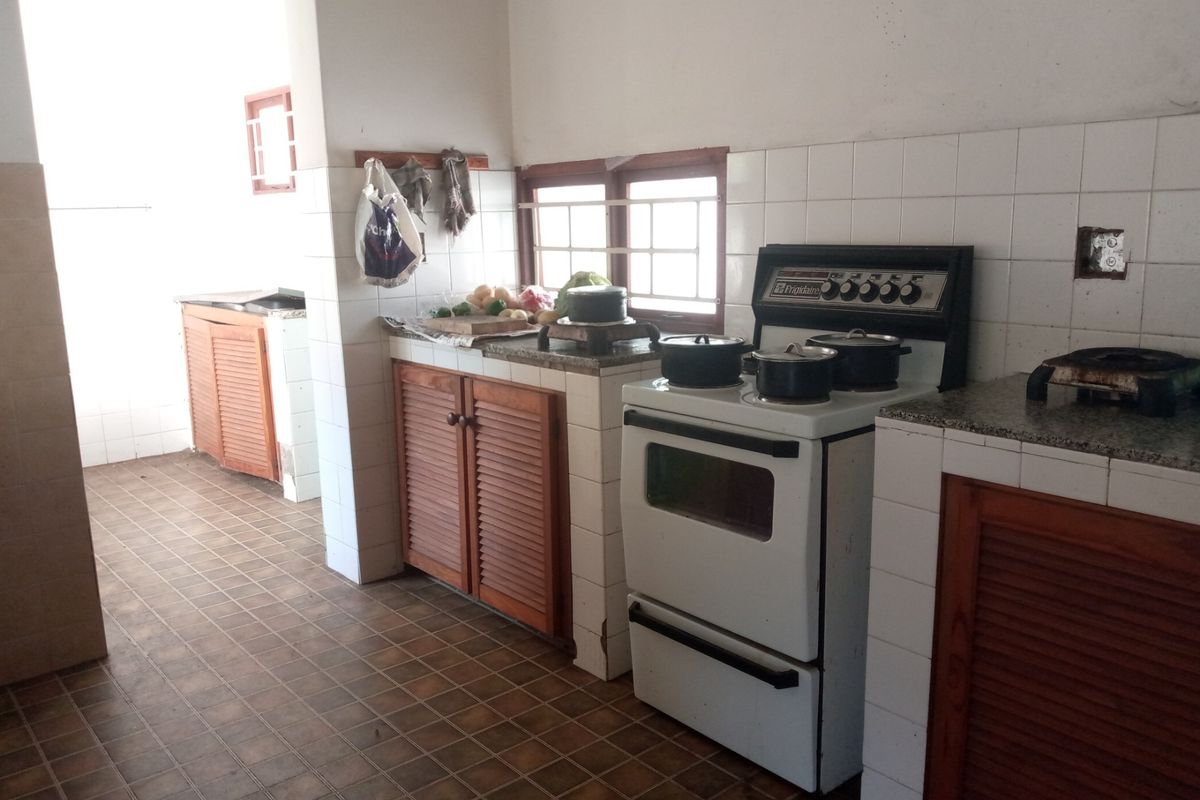 A dated kitchen featuring louvered wooden cabinetry, granite countertops, tiled splashbacks, and a freestanding oven, offering potential for a modern renovation.