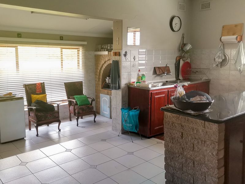 A dated kitchen featuring a brick breakfast bar, granite countertops, and a built-in brick oven alcove, offering potential for a modern renovation.