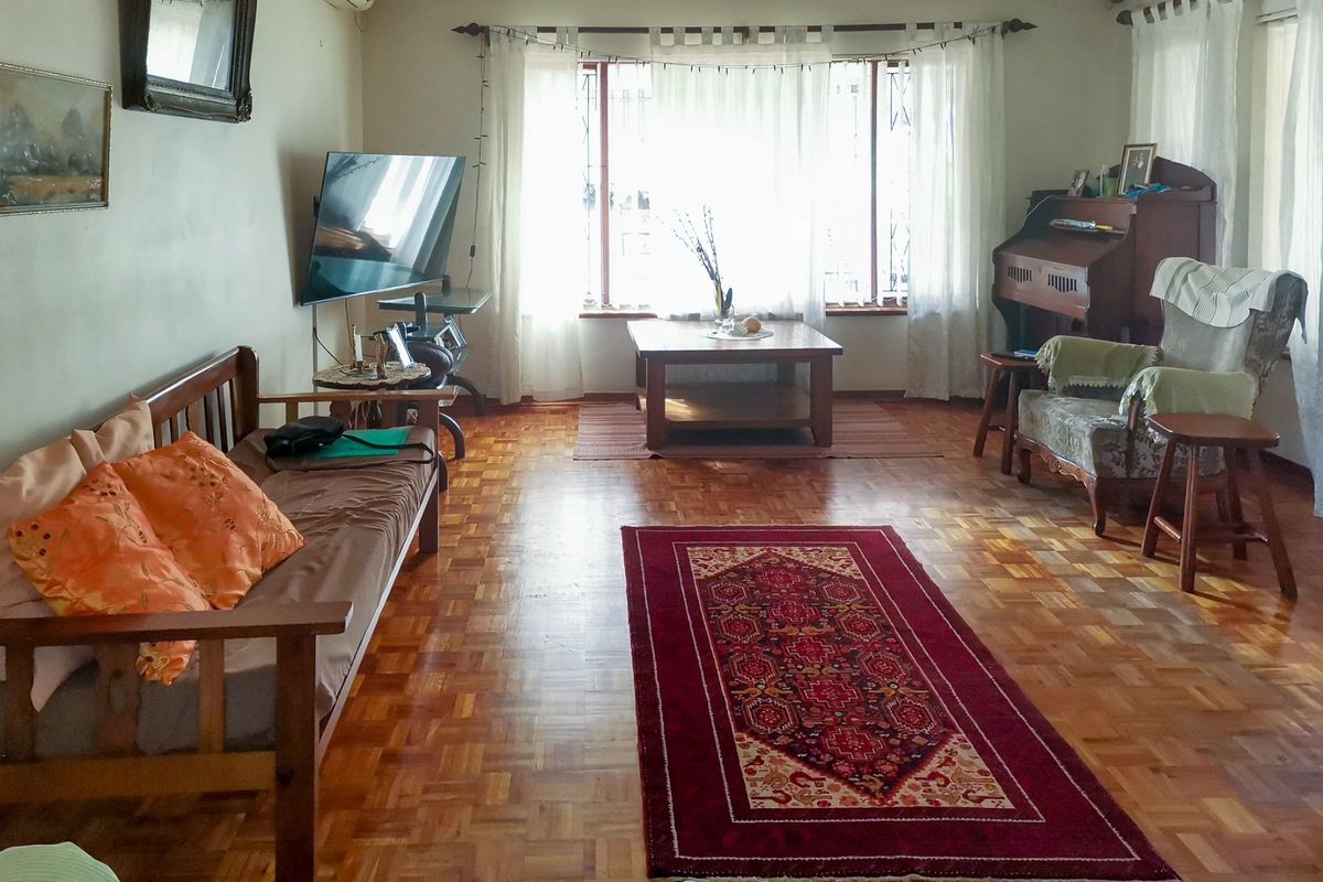 A spacious living room featuring classic parquet flooring and a large window that allows for ample natural light.