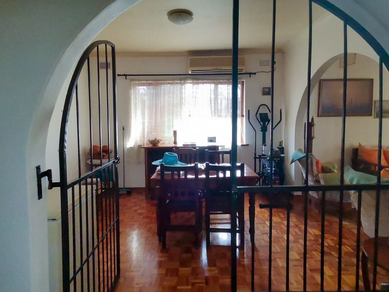 Living area featuring classic parquet flooring, an arched entryway with a security gate, and a wall-mounted air conditioning unit.