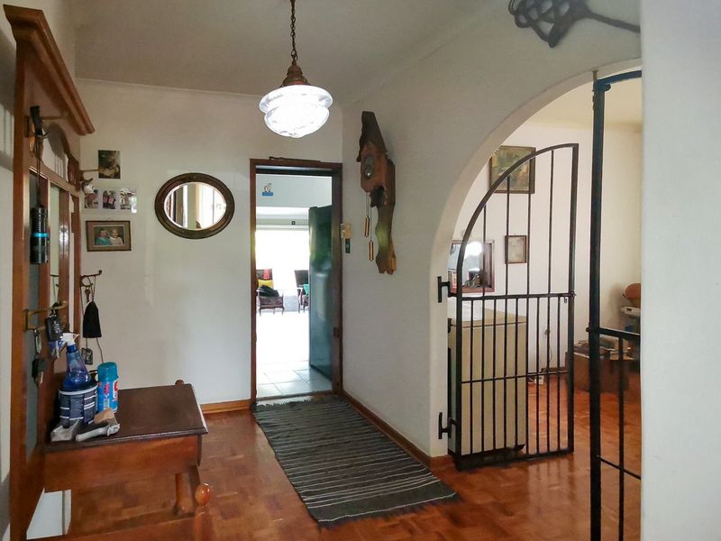 Entrance hall featuring parquet flooring, an arched doorway with a wrought iron security gate, and a classic pendant light fixture.