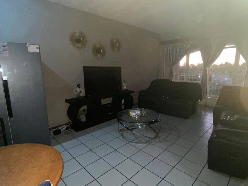 A living room area featuring tiled flooring and a sliding glass door providing natural light.
