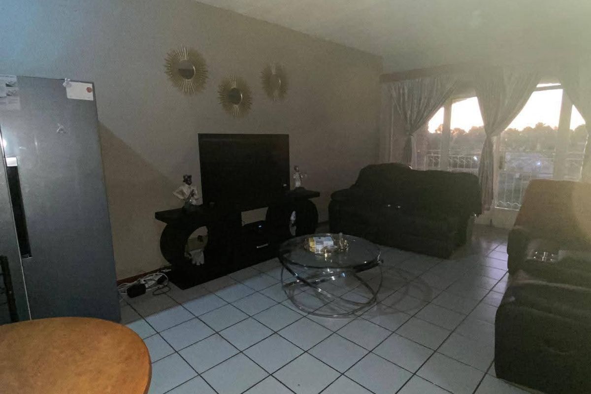 A living room area featuring tiled flooring and a sliding glass door providing natural light.