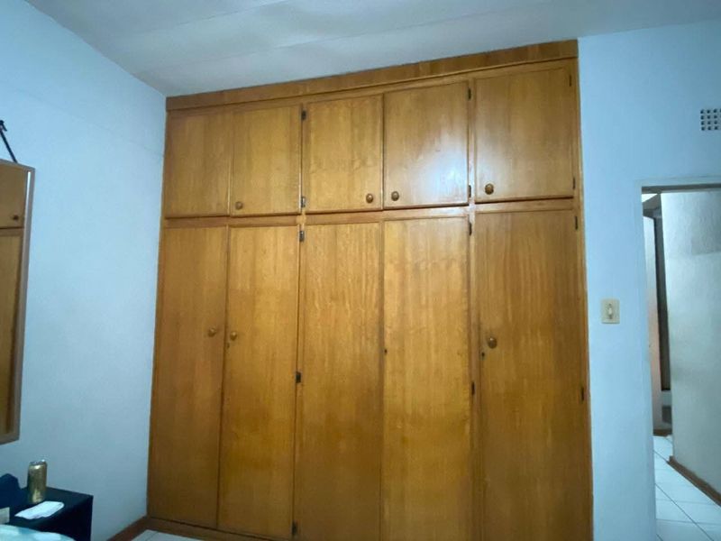 A bedroom featuring floor-to-ceiling built-in wooden cupboards providing ample storage space.