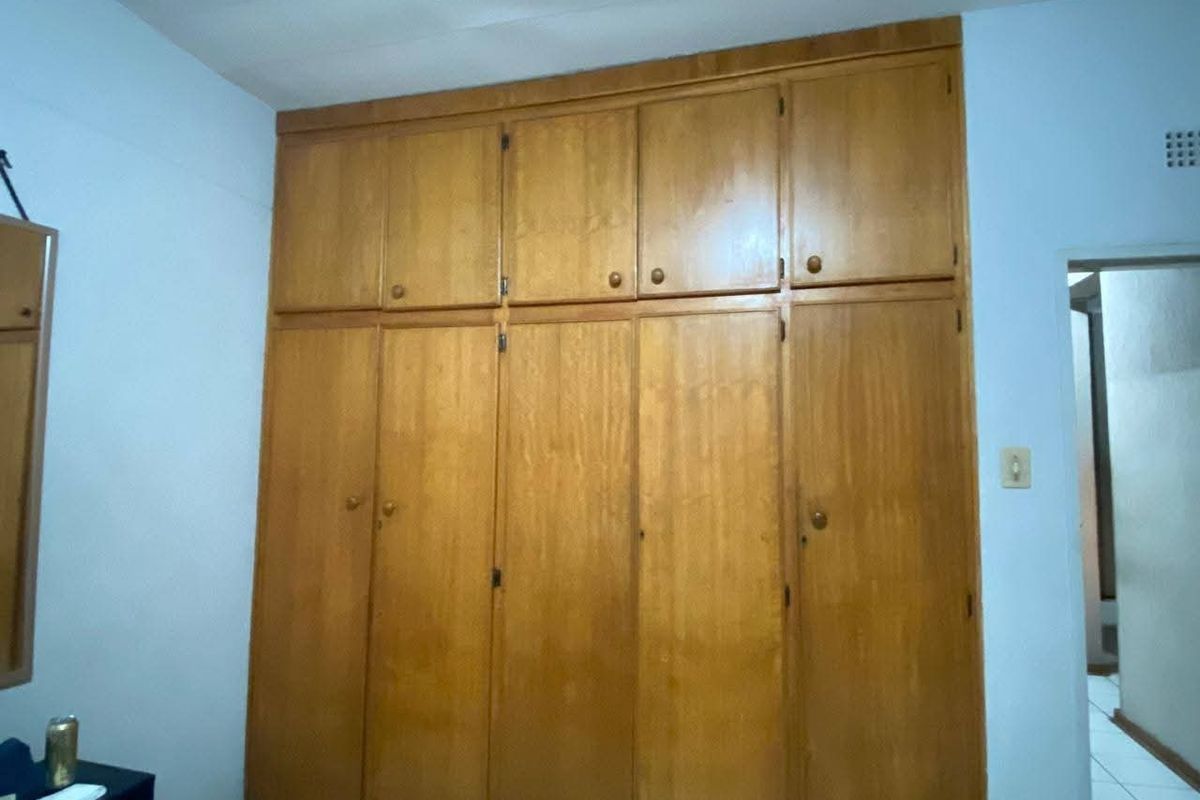 A bedroom featuring floor-to-ceiling built-in wooden cupboards providing ample storage space.