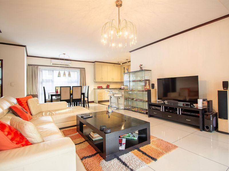 Spacious open-plan living and dining area featuring tiled floors, modern kitchen cabinetry, and a split-system air conditioner for climate control.
