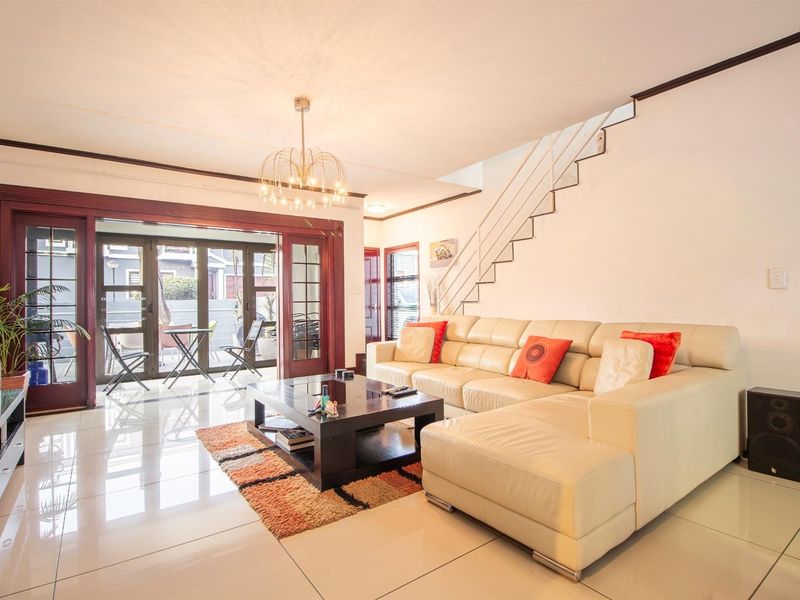 Spacious living room featuring polished tile flooring, a modern staircase with metal railings, and large sliding glass doors opening to an outdoor patio area.