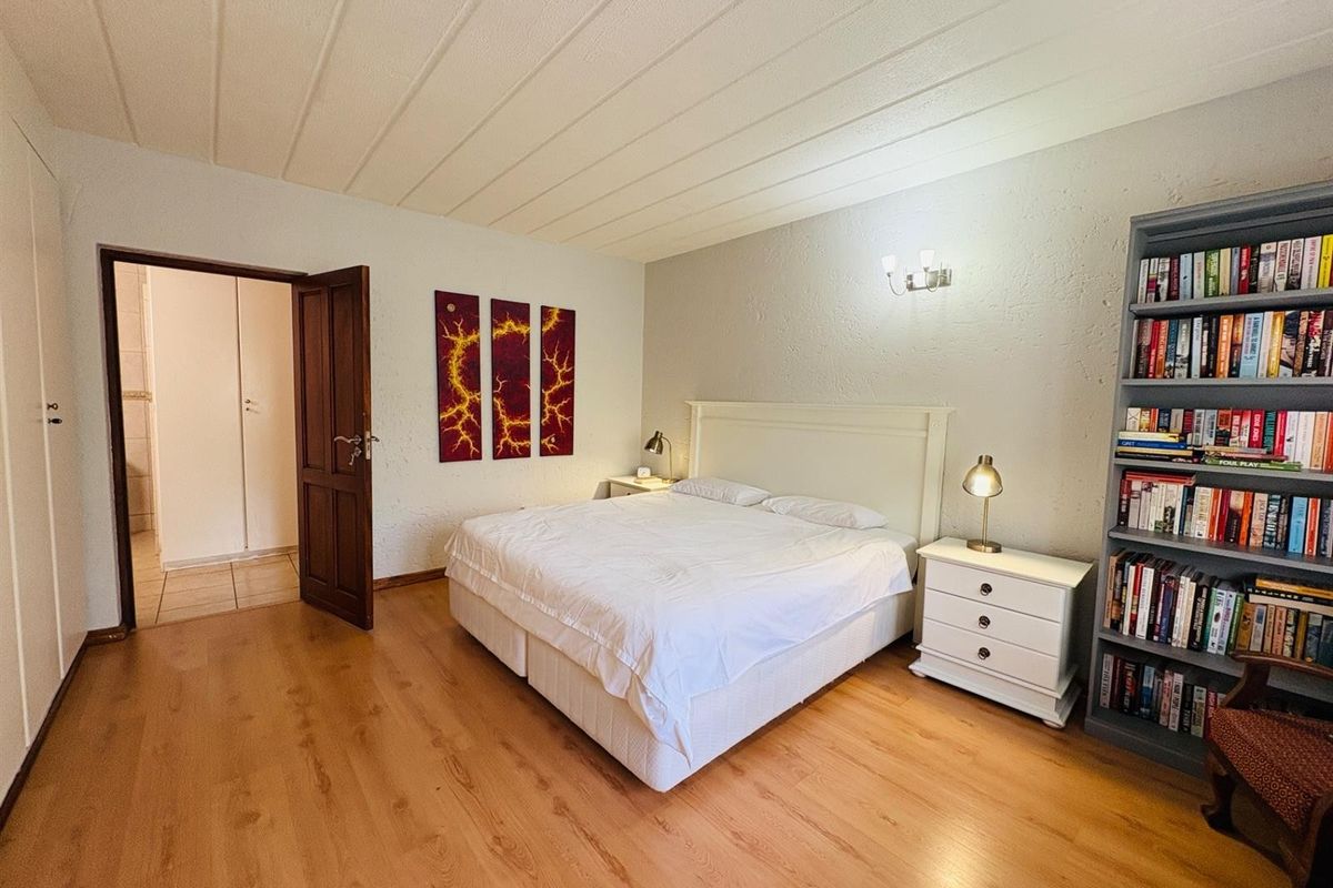 A spacious bedroom featuring laminate flooring, a textured ceiling, and a neutral color palette, offering a comfortable and functional living space.