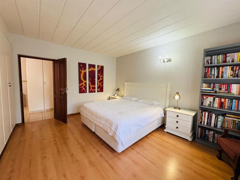 A spacious bedroom featuring laminate flooring, a textured ceiling, and a neutral color palette, offering a comfortable and functional living space.