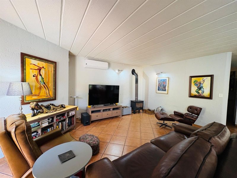 Spacious living room featuring tiled flooring, a wood-burning stove, and a wall-mounted air conditioning unit.