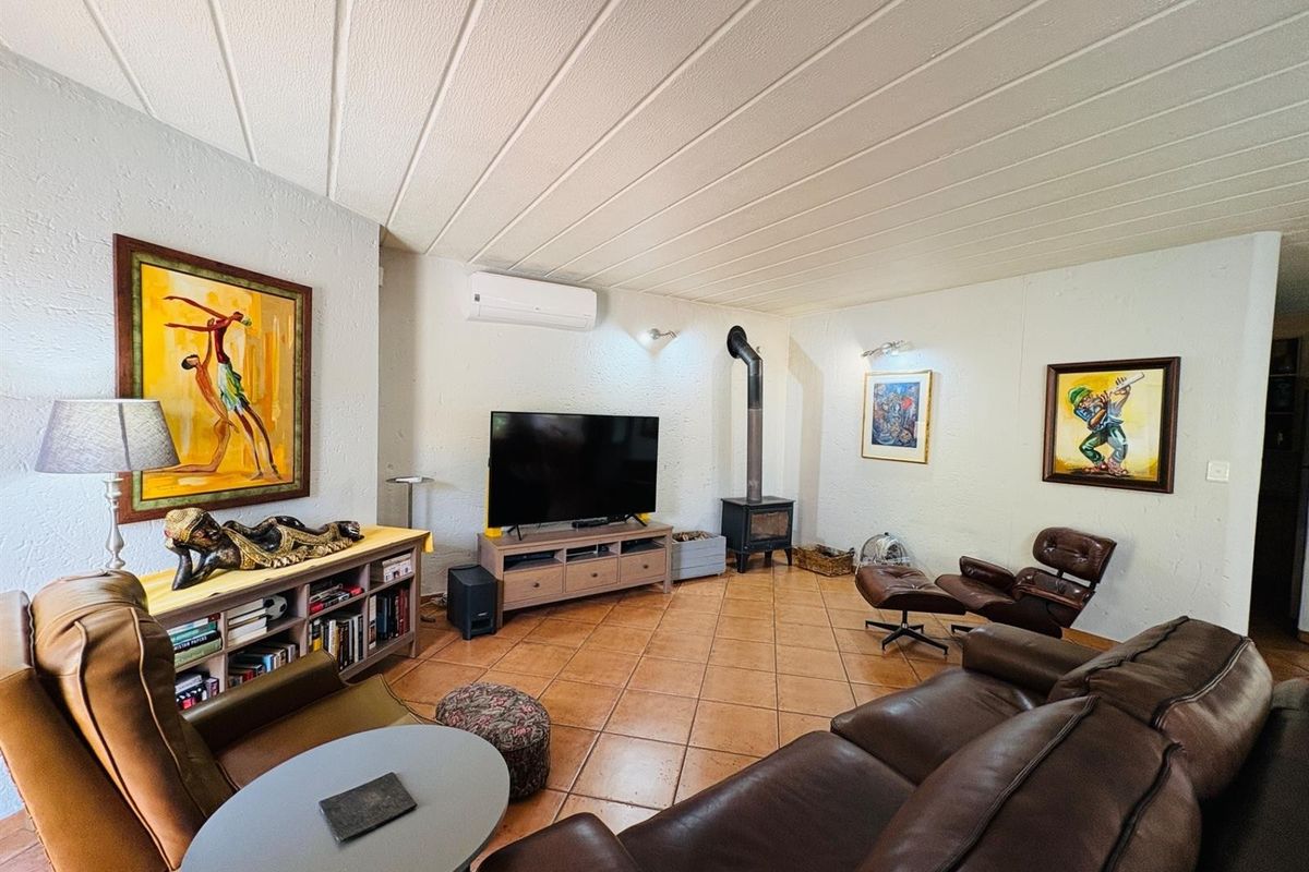 Spacious living room featuring tiled flooring, a wood-burning stove, and a wall-mounted air conditioning unit.
