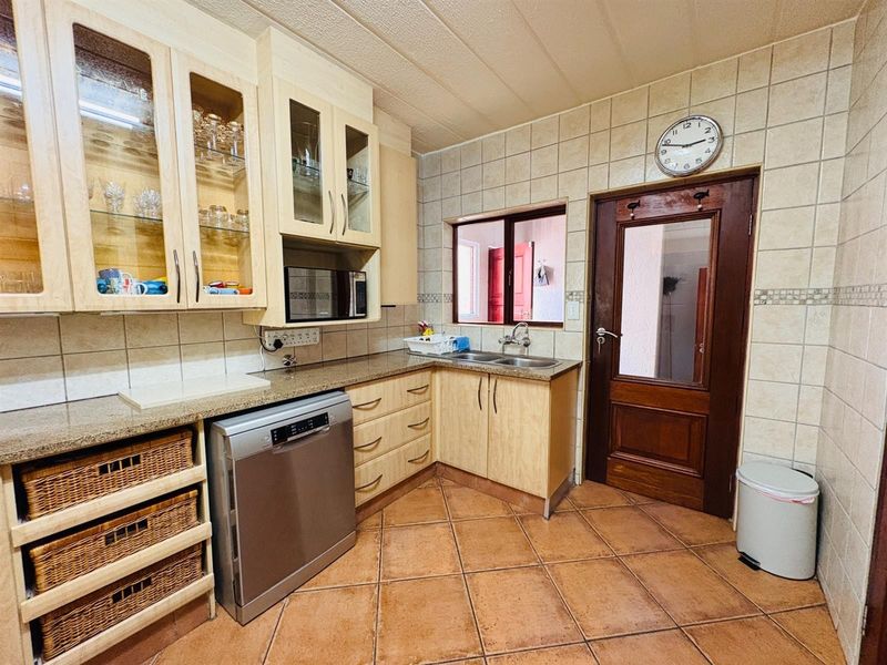 A functional kitchen featuring light wood cabinetry, granite countertops, tiled backsplash, and tiled flooring, offering a practical layout with ample storage space.