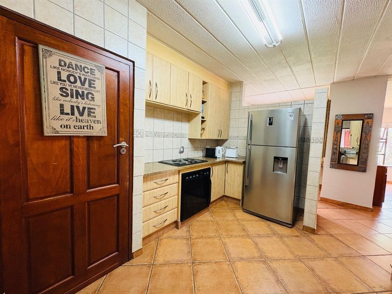 A functional kitchen featuring light wood cabinetry, granite countertops, built-in oven and hob, and tiled flooring throughout.