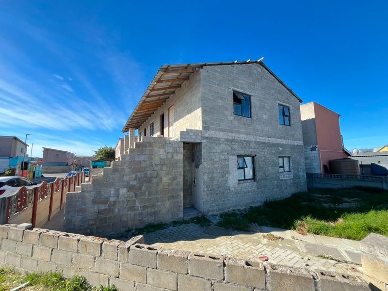 A two-story residential property currently under construction, featuring exposed concrete block walls and an unfinished roof structure.