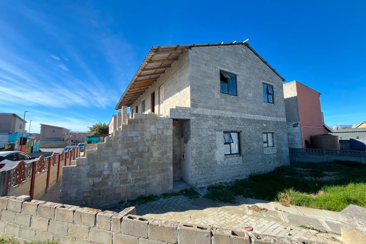 A two-story residential property currently under construction, featuring exposed concrete block walls and an unfinished roof structure.