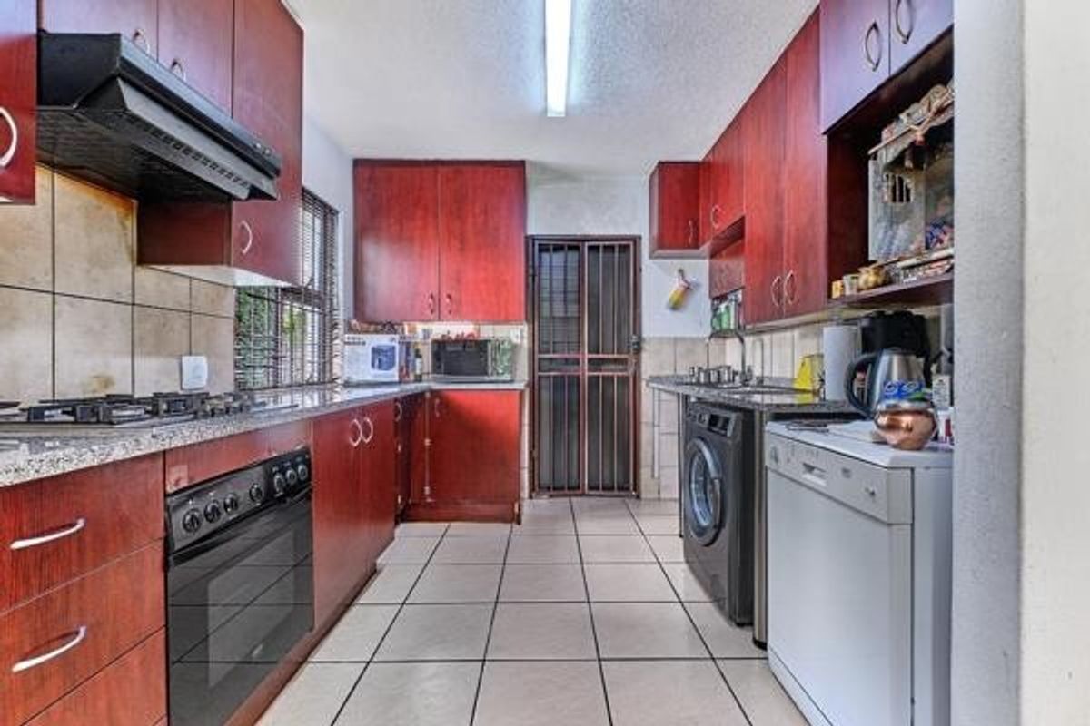 Functional kitchen featuring dark wood cabinetry, granite countertops, built-in oven with gas hob, and tiled flooring with direct access to the exterior.