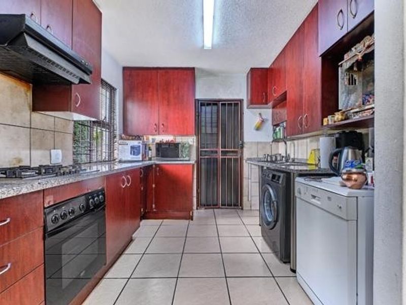 Functional kitchen featuring dark wood cabinetry, granite countertops, built-in oven with gas hob, and tiled flooring with direct access to the exterior.