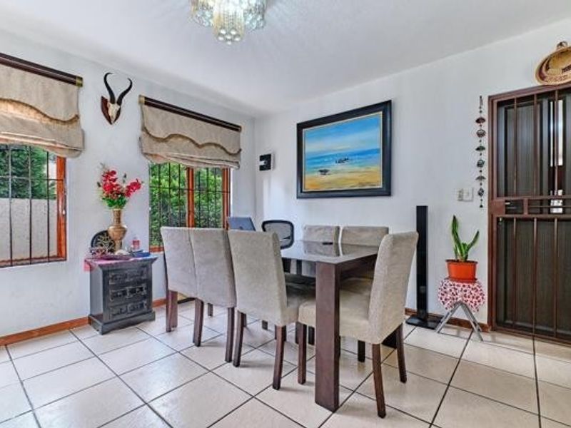 A dining room featuring tiled flooring, security bars on the windows, and a secure metal entrance door.