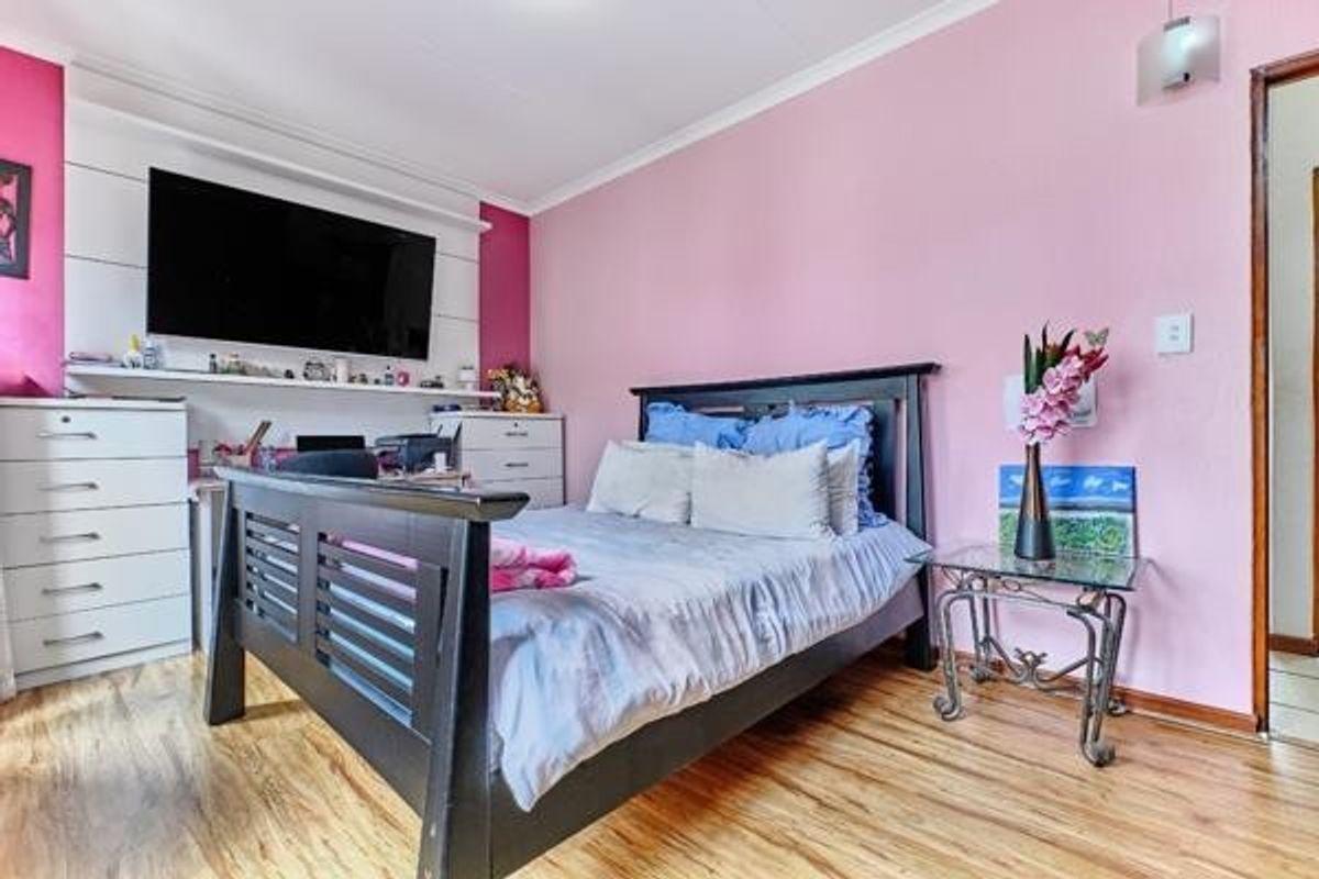 A bedroom featuring laminate flooring, built-in shelving, and a wall-mounted light fixture, providing a functional space with potential for modern updates.