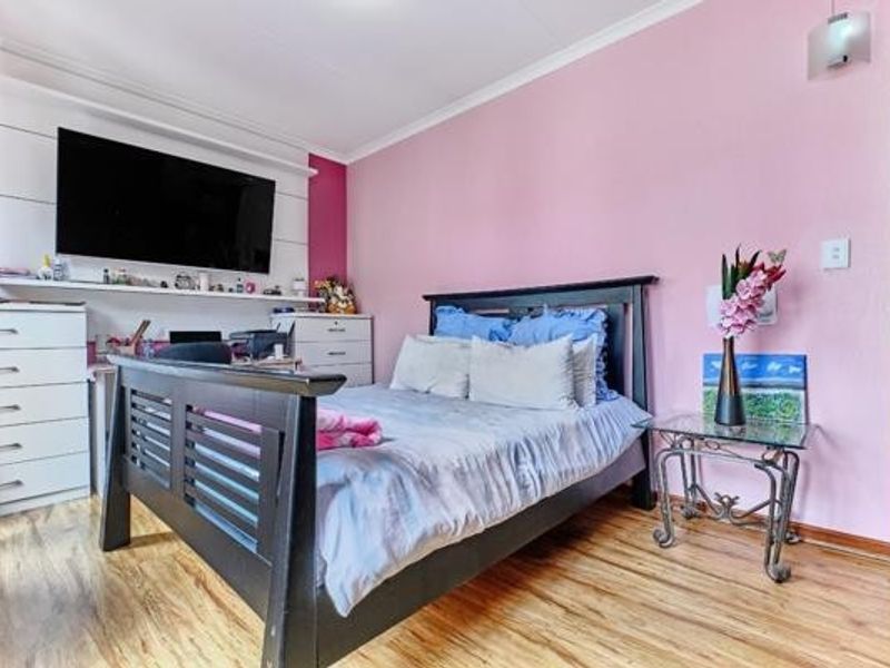 A bedroom featuring laminate flooring, built-in shelving, and a wall-mounted light fixture, providing a functional space with potential for modern updates.
