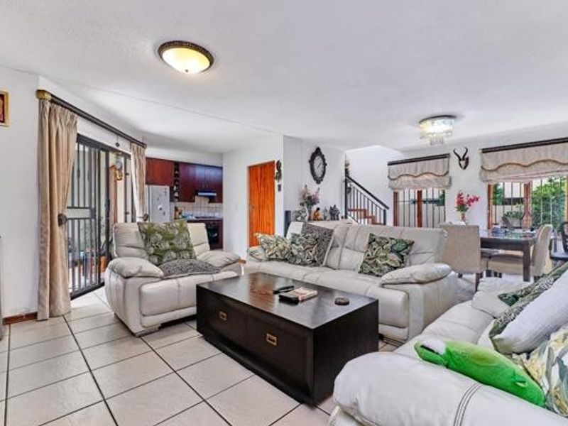 Spacious open-plan living area featuring tiled flooring, integrated kitchen cabinetry, and direct access to an outdoor patio through a sliding glass door.