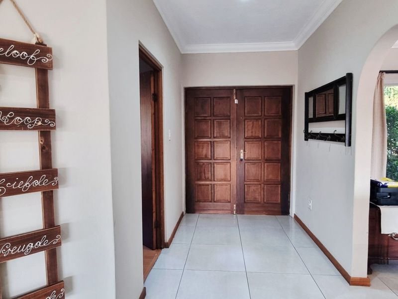 Welcoming entrance hall featuring tiled flooring, a classic archway leading to the living area, and solid wooden double doors.