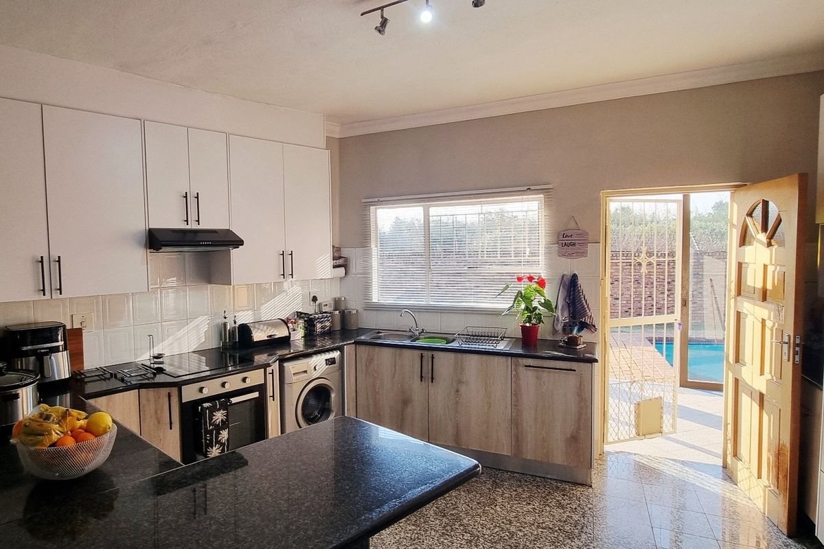 Modern kitchen featuring white and wood-grain cabinetry, granite countertops, built-in appliances, and direct access to the outdoor pool area.