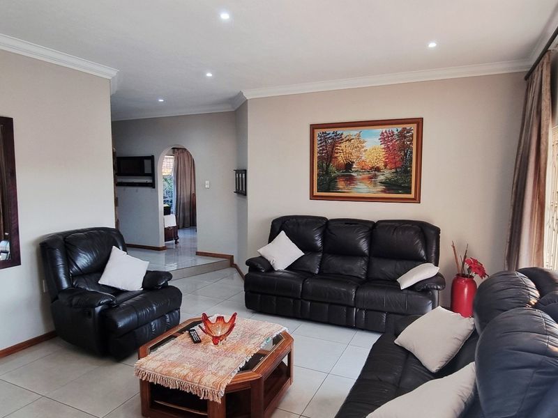 A well-maintained living room featuring tiled flooring, recessed downlighting, and a decorative archway leading to adjacent living spaces.