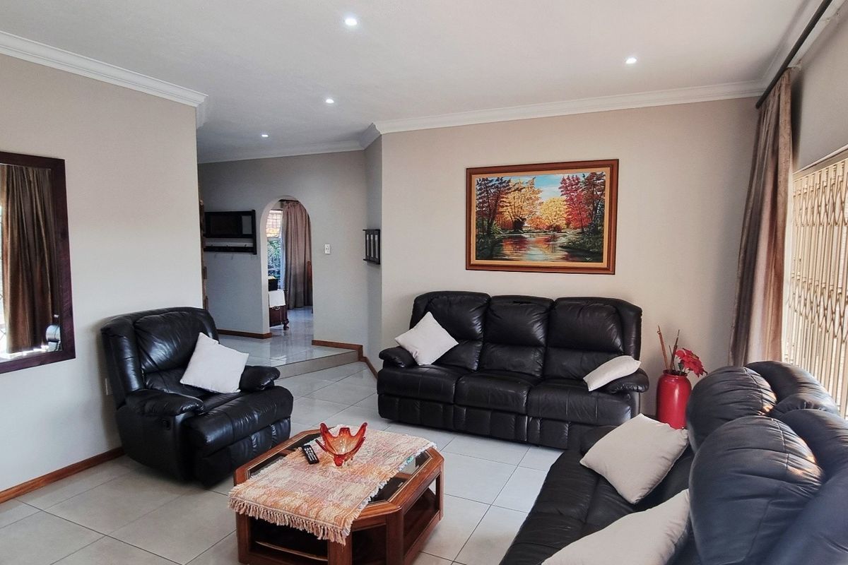 A well-maintained living room featuring tiled flooring, recessed downlighting, and a decorative archway leading to adjacent living spaces.