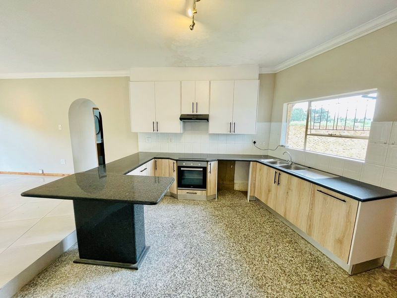 A functional kitchen featuring light wood cabinetry, dark granite countertops, built-in oven, extractor fan, and a breakfast bar peninsula.