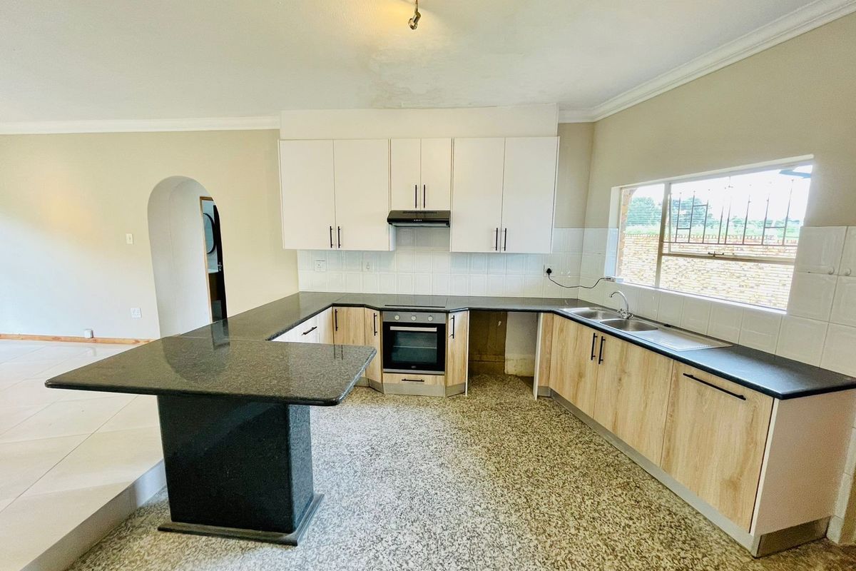 A functional kitchen featuring light wood cabinetry, dark granite countertops, built-in oven, extractor fan, and a breakfast bar peninsula.
