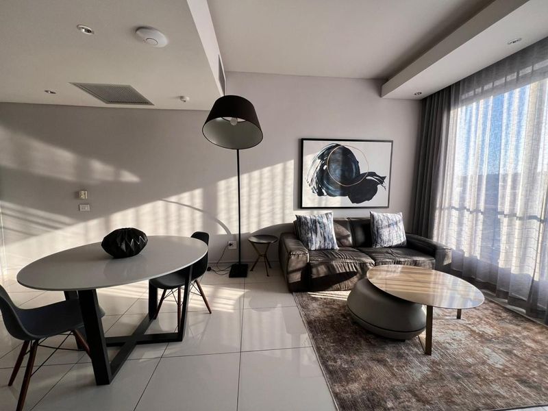 A modern open-plan living and dining area featuring sleek tiled flooring, recessed lighting, and large windows with layered curtains for natural light control.