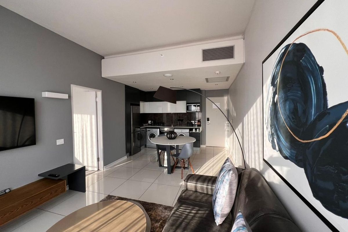Modern open-plan living area featuring a sleek kitchen with built-in cabinetry, integrated appliances, and polished tiled flooring throughout.