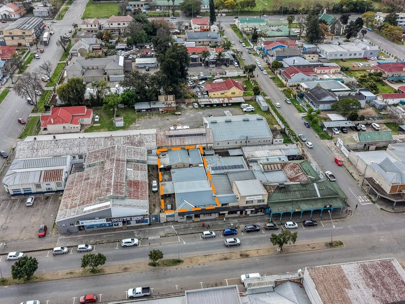 Aerial view of a commercial property complex featuring multiple buildings with corrugated metal roofing and adjacent street-level parking in an urban setting.