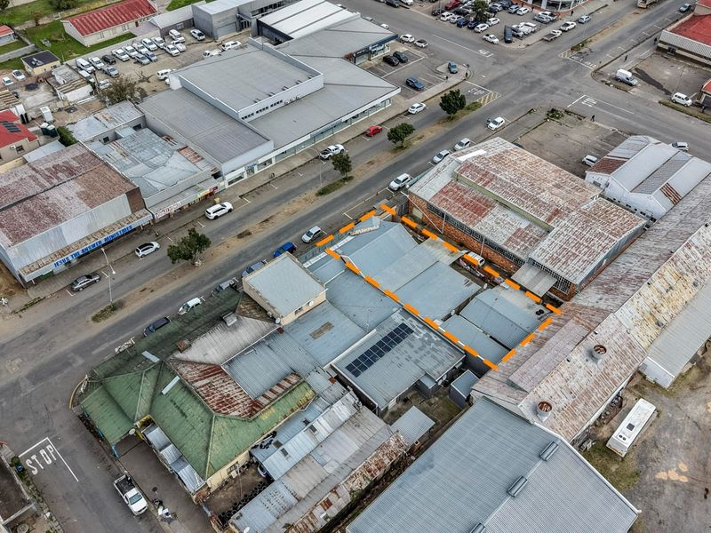 Aerial view of a commercial property complex featuring multiple corrugated metal roof sections and integrated solar panels within an urban street setting.