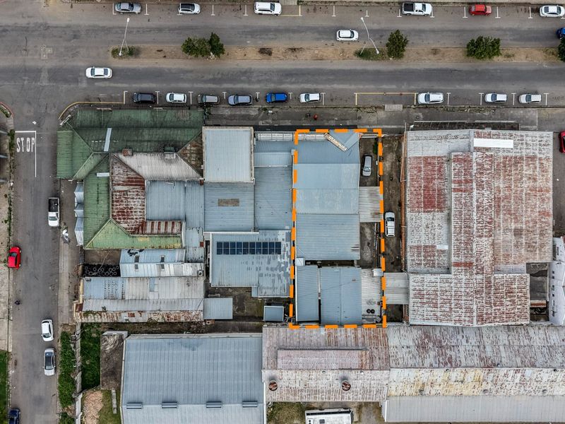 Aerial view of the property showing the building footprint, corrugated metal roof structure with solar panels, and adjacent street parking.
