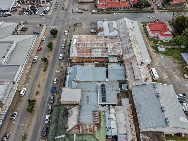 Aerial view of a commercial property complex featuring multiple interconnected buildings with corrugated metal roofing and adjacent paved parking areas.