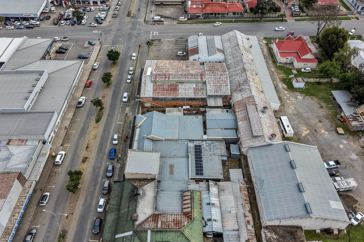 Aerial view of a commercial property complex featuring multiple interconnected buildings with corrugated metal roofing and adjacent paved parking areas.