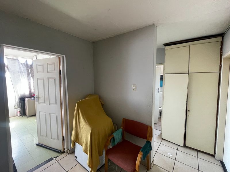 Bedroom featuring built-in cupboards and tiled flooring, with an adjacent doorway leading to a bathroom area.