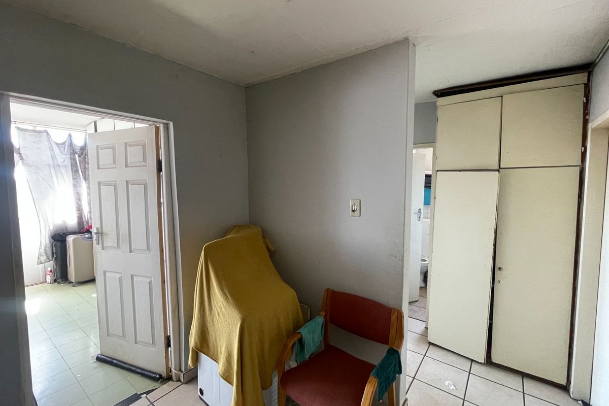 Bedroom featuring built-in cupboards and tiled flooring, with an adjacent doorway leading to a bathroom area.