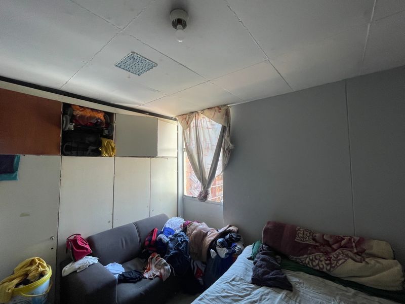 A bedroom featuring built-in cupboards and a window, requiring cosmetic updates and repairs to the ceiling and cabinetry to improve its overall condition.
