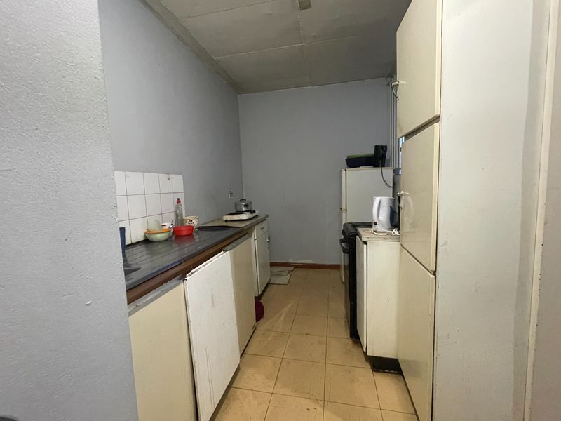 A dated kitchen featuring basic cabinetry, tiled flooring, and a stainless steel sink, offering significant potential for modernization and renovation.