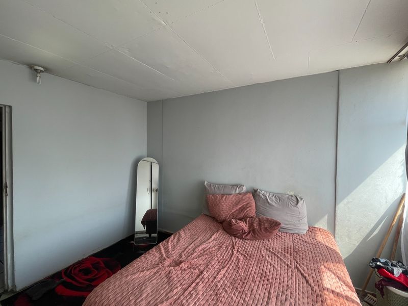 A simple bedroom featuring plain walls and a visible ceiling panel structure, offering a blank canvas for potential interior updates.