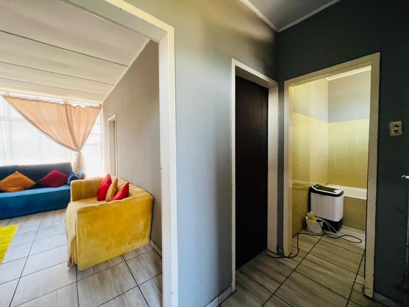 A view from the hallway looking into the living area and bathroom, featuring tiled flooring and neutral wall finishes.